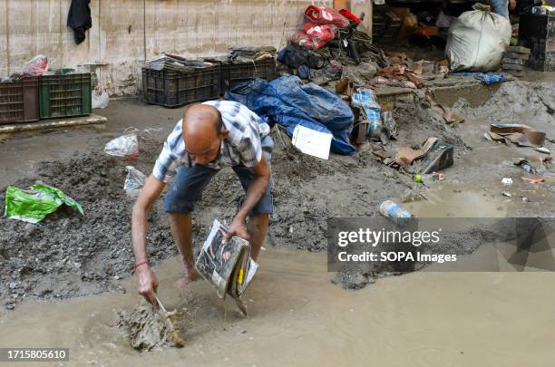 Swaminath Shah cleans up belongings from his shop in the muddy water after it was buried by flash floods following the eruption of a lake in Singtam....