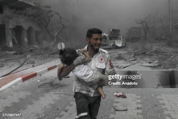 Medical worker rushes a child to the ambulance for treatment after Israeli airstrikes destroy buildings in Gaza City, Gaza on October 09, 2023.