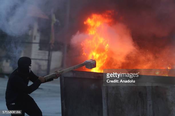 Palestinians use trash containers as covers and set them on fire in response to Israeli forces' interventions as they clash at Beit El district of...