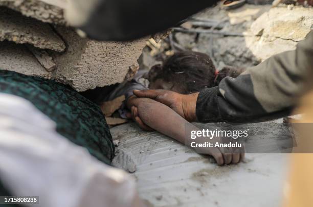 Rescuer pulls out the dead body of a little girl from the rubble after Israeli airstrikes in Gaza City, Gaza on October 09, 2023. Search and rescue...