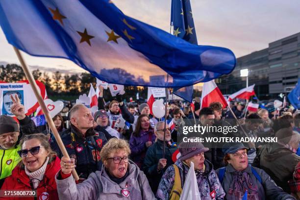 People wave Polish and EU flags as they gather outside a tv studio where main candidates in the upcoming Polish elections are taking part in a debate...