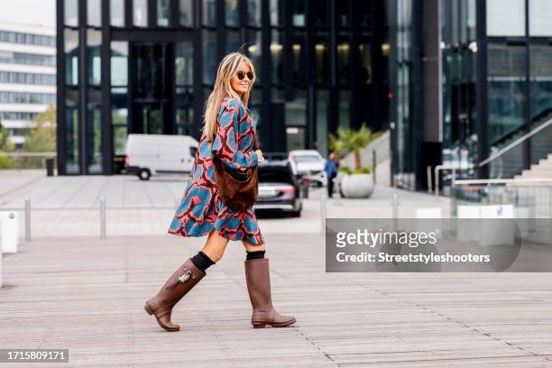 Influencer Gitta Banko, wearing a red-blue dress by Odeeh, brown boots by Dorothee Schumacher, a brown bag by Khaite New York, sunglasses by Ray Ban...