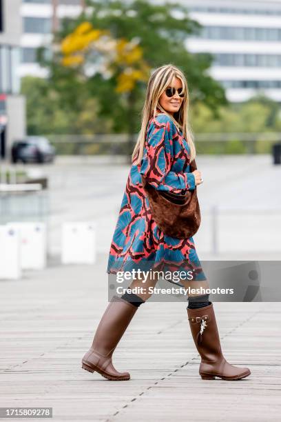 Influencer Gitta Banko, wearing a red-blue dress by Odeeh, brown boots by Dorothee Schumacher, a brown bag by Khaite New York, sunglasses by Ray Ban...