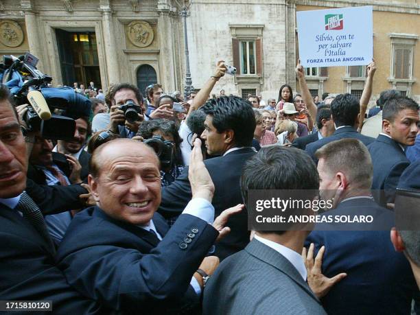 Italian Prime Minister Silvio Berlusconi surrounded by his bodyguards leaves Rome's Palazzo Montecitorio, the lower house building, at the end of his...