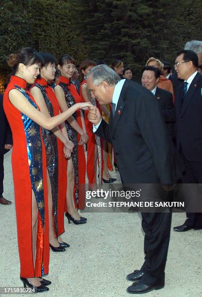 French Prime Minister Jean-Pierre Raffarin kisses the hand of a young Chinese hostess as Li Changchun of the Chinese Communist Party Polit Bureau...