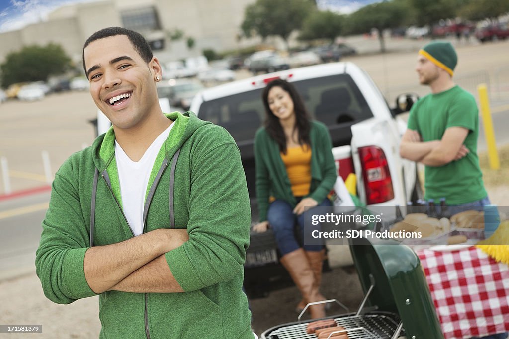 Happy football fan tailgating with friends near stadium