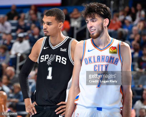 Victor Wembanyama of the San Antonio Spurs and Chet Holmgren of the Oklahoma City Thunder look on during the game on October 9, 2023 at the Paycom...