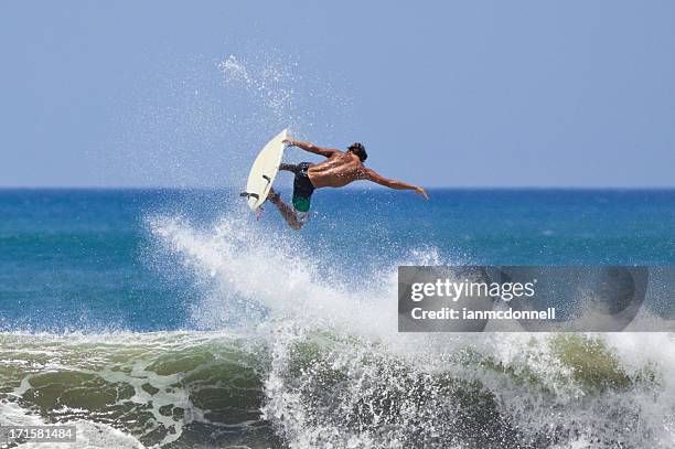 a man surfing and hitting big air above a wave - air waves stockfoto's en -beelden