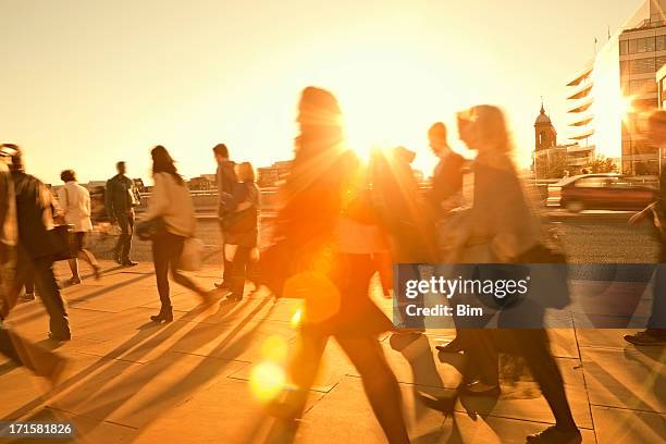 business commuters walking home after work, sunset backlit, blurred motion - tegenlicht stockfoto's en -beelden
