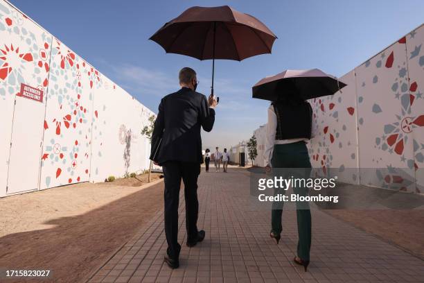 Attendees shelter from the sun under umbrellas at the annual meetings of the International Monetary Fund and World Bank in Marrakesh, Morocco, on...