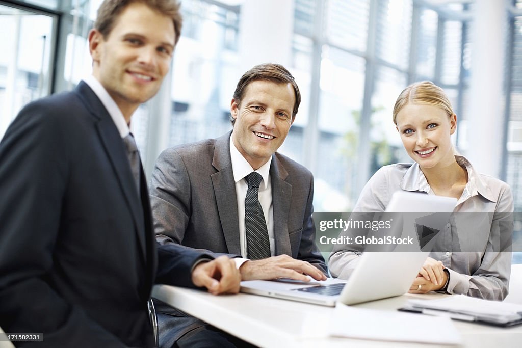 Happy executives in meeting working on laptop