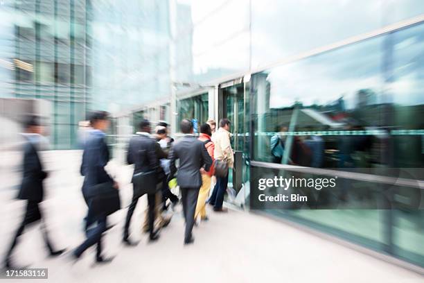 blurred business people entering office building through glass doors - betreden stockfoto's en -beelden