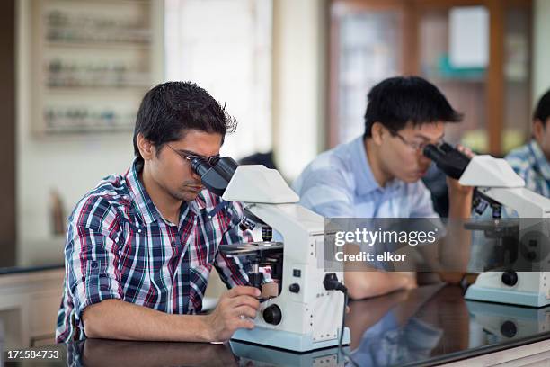 indian students looking through microscope  in a laboratory - india lab stockfoto's en -beelden