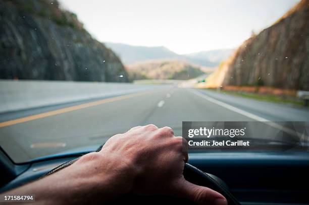 driver's hand on the wheel driving down highway - steering wheel stock pictures, royalty-free photos & images