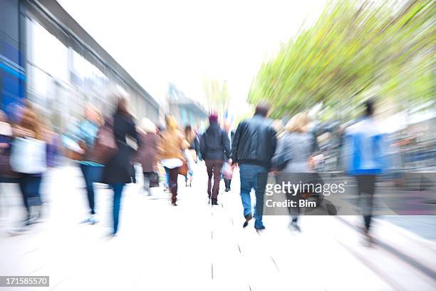 crowd of people walking down walkway past stores, blurred motion - shopping crowd stock pictures, royalty-free photos & images