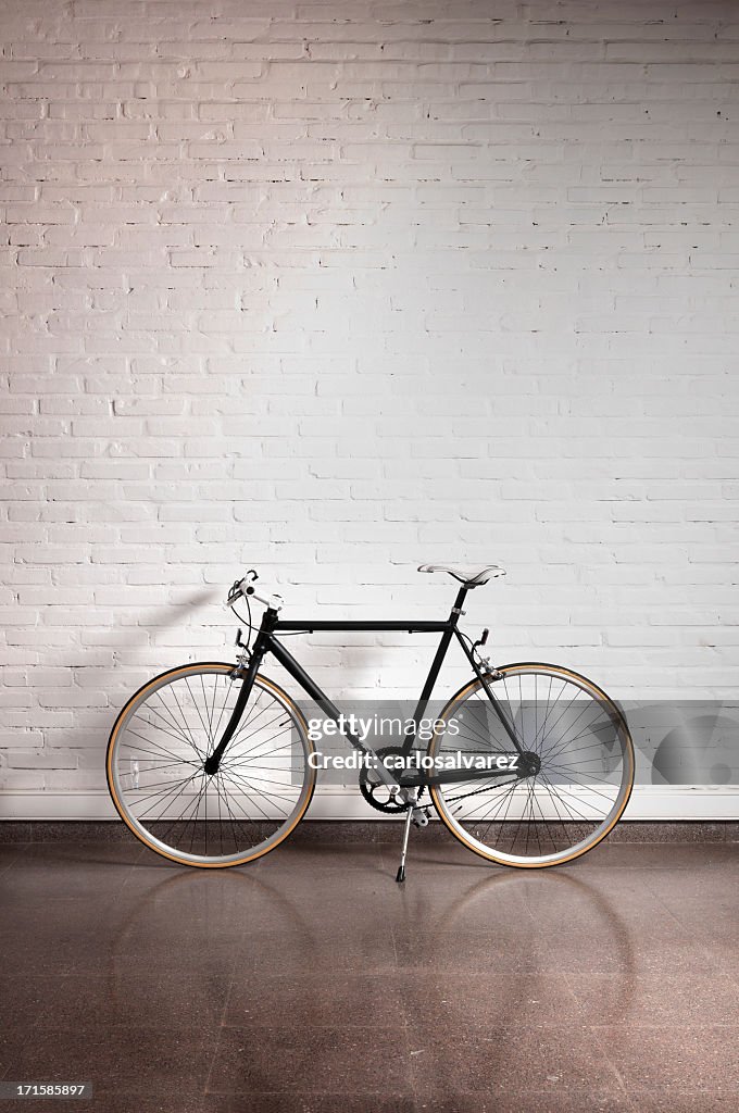 Black bicycle by a white brick wall