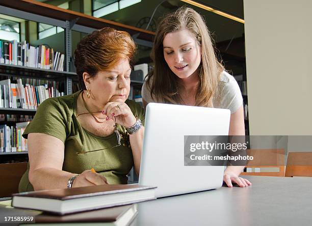 bibliotecário ajuda a mulher idosa com computador portátil - teching imagens e fotografias de stock