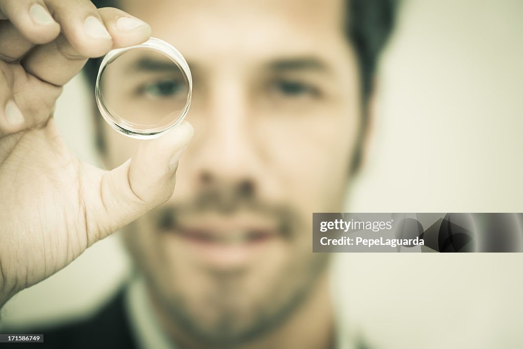 Businessman looking through a round lens