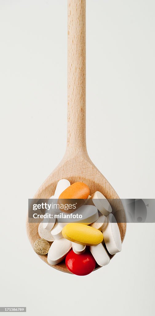 Pills on a wooden spoon