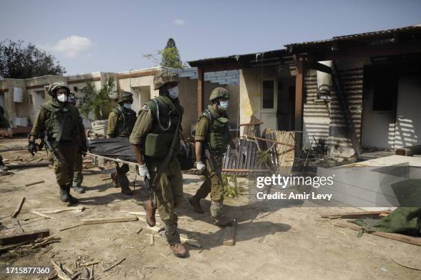 Israeli soldiers remove the body of a civilian, who was killed days earlier in an attack by Palestinian militants on this kibbutz near the border...