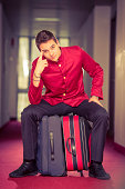 Bell boy sitting on suitcase