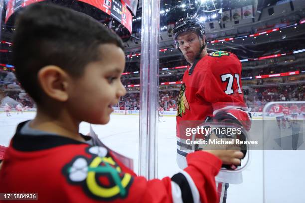 Taylor Hall of the Chicago Blackhawks hands a puck to a young fan prior to the preseason game against the Detroit Red Wings at the United Center on...