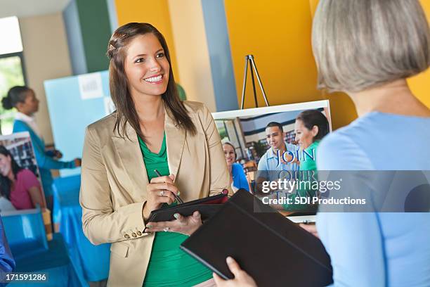 professional businesswoman using digital tablet interviewing at job fair event - job fair stock pictures, royalty-free photos & images
