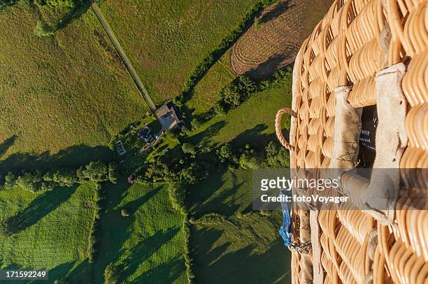 dramatic aerial view from balloon basket over green fields - hot air balloon basket stock pictures, royalty-free photos & images