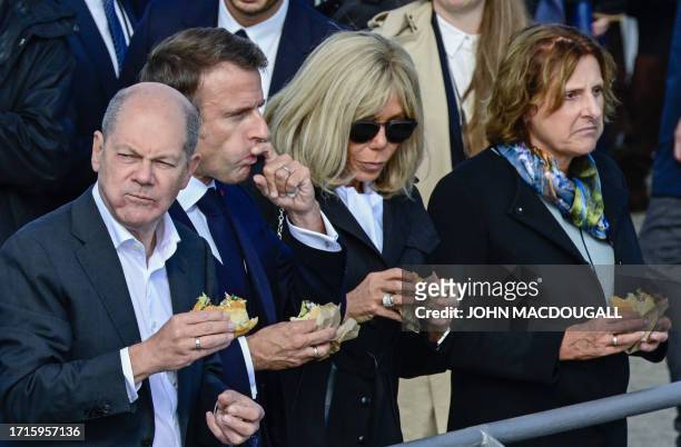 German Chancellor Olaf Scholz and his wife Britta Ernst , French President Emmanuel Macron and French first lady Brigitte Macron eat a fish sandwich...