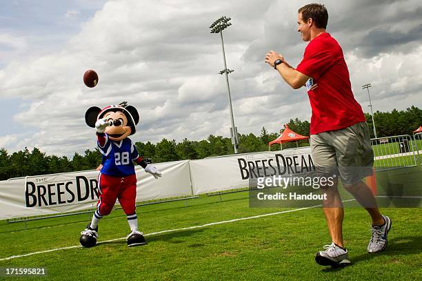 In this handout photo provided by Disney Parks, New Orleans Saints All-Pro quarterback Drew Brees catches a pass from Mickey Mouse at the ESPN Wide...