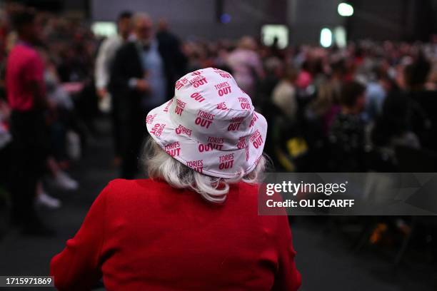 Delegate wearing a bucket hat with the slogan 'Tories Out' walks in the conference hall on the third day of the annual Labour Party conference in...