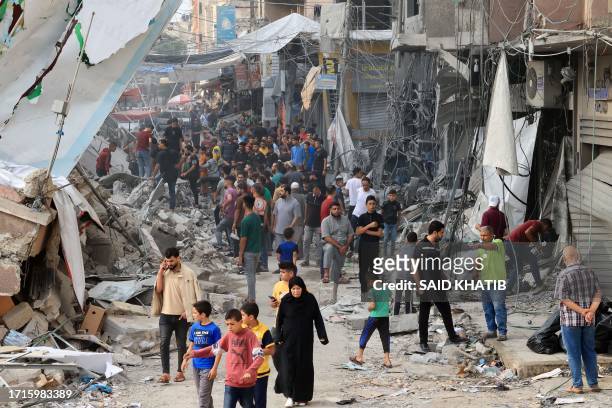 Palestinians walk amid the rubble of destroyed and damaged building in the heavily bombarded city center of Khan Yunis in the southern Gaza Strip...