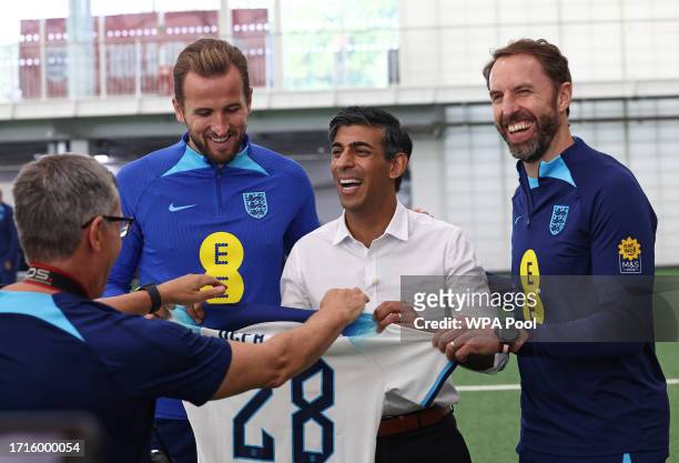 Britain's Prime Minister Rishi Sunak poses with an England shirt alongside England striker Harry Kane and England manager Gareth Southgate during an...