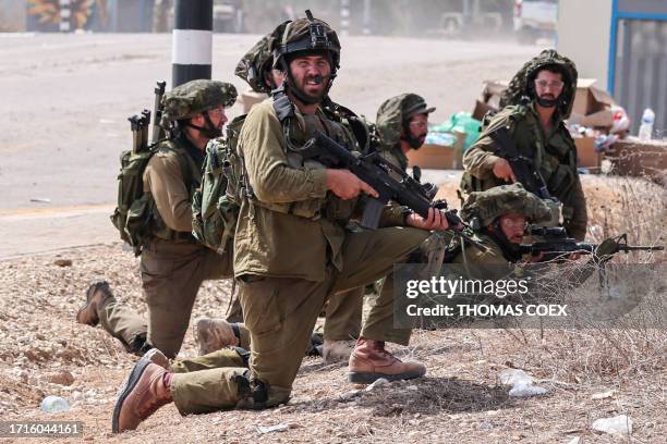 Israeli soldiers take position next to a road in Kfar Aza, south of Israel bordering the Gaza Strip, on October 10 following fighting between Israeli...