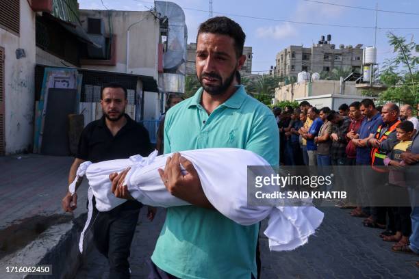 Palestinian man carries the body of a child killed in overnight Israeli shelling during a funeral in Khan Yunis in the southern Gaza Strip, on...