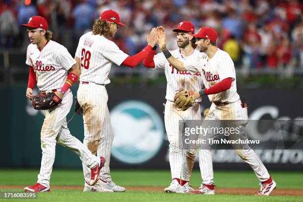 Bryson Stott, Alec Bohm, Bryce Harper, and Trea Turner of the Philadelphia Phillies celebrate defeating the Miami Marlins 4-1 in Game One of the Wild...