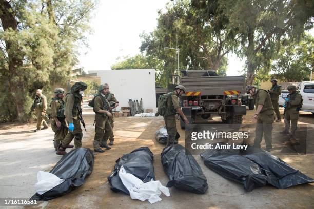 Israeli soldiers remove the bodies of civilians, who were killed days earlier in an attack by Palestinian militants on this kibbutz near the border...