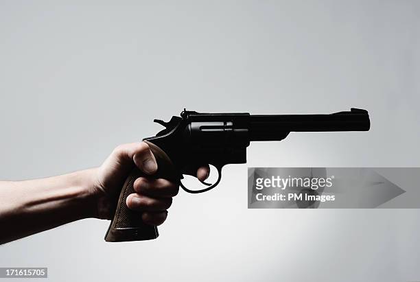 man's hand holding pistol - revolver stock-fotos und bilder