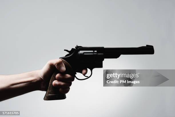 man's hand holding pistol - armi da fuoco foto e immagini stock