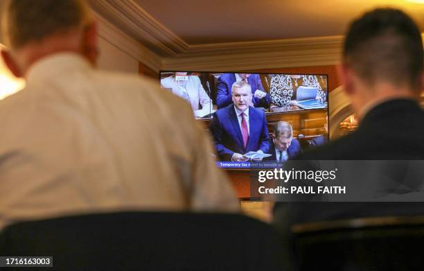 People watch a television showing a live broadcast of Ireland's Finance Minister Michael McGrath presenting the 2024 Irish Budget to Parliament, from...