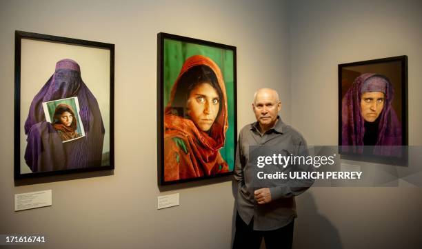 Photographer Steve McCurry poses next to his photos of the "Afghan Girl" named Sharbat Gula at the opening of the "Overwhelmed by Life" exhibition of...