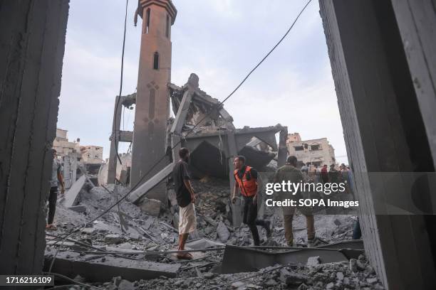 Emergency personnel and Palestinians inspect damages in the aftermath of Israeli strikes, following a Hamas surprise attack, at Beach refugee camp,...