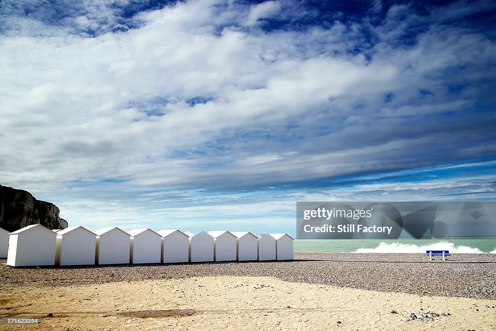 White beach huts in a row on shingle beach