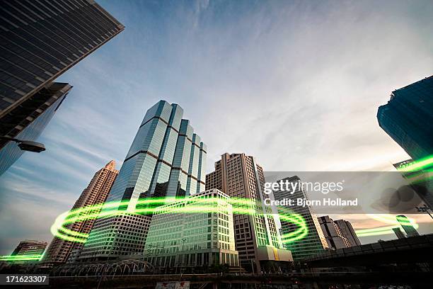 green light trails surrounding skyscrapers - circondare foto e immagini stock