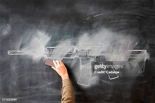 person erasing chalk drawing of gun on blackboard - terrorist attack stock pictures, royalty-free photos & images