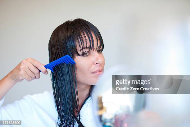 mid adult woman combing wet hair - cabello mojado fotografías e imágenes de stock