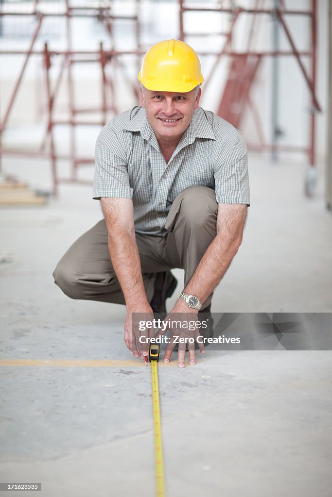 Builder measuring floor space on construction site