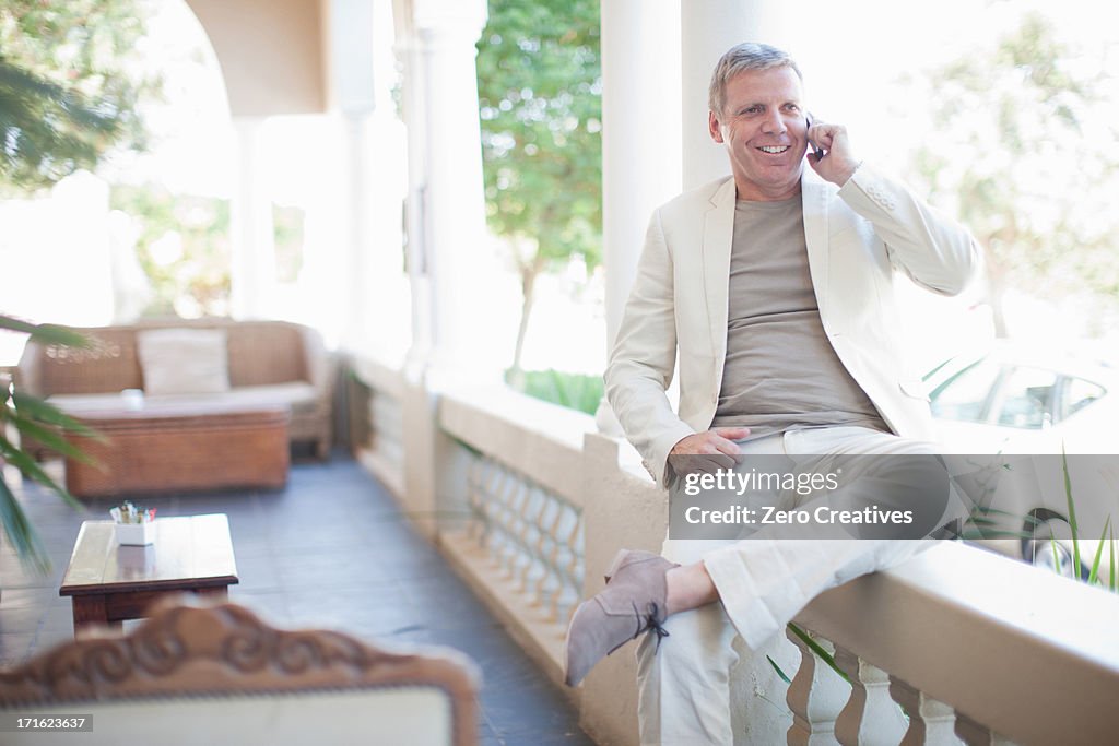 Mature man sitting on wall on smartphone