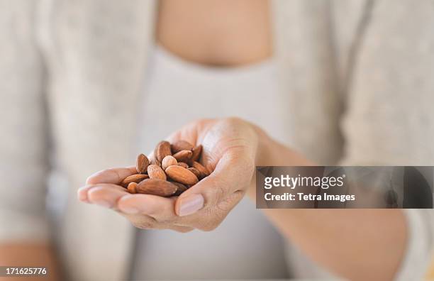 usa, new jersey, jersey city, close-up of woman holding almonds - handvol stockfoto's en -beelden