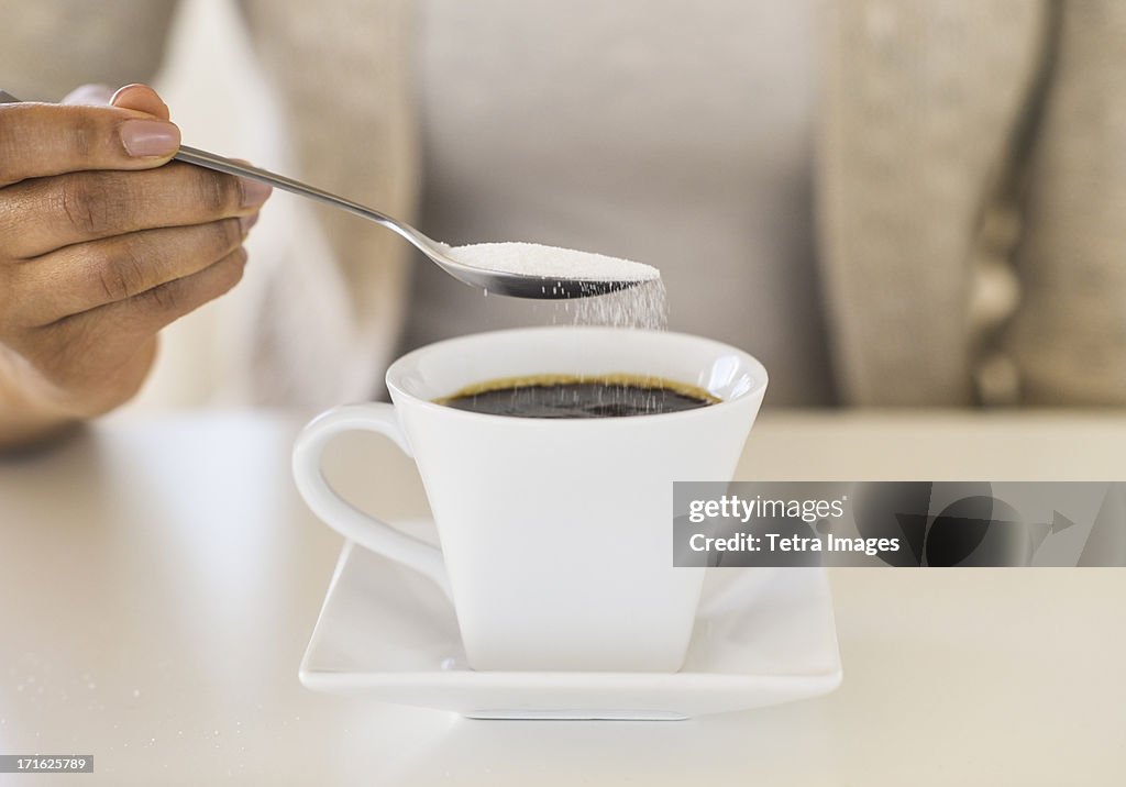 USA, New Jersey, Jersey City, Close-up of woman sweetening coffee